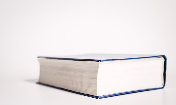 Closed thick book with white cover placed on white background, side view. Book, closed, thick, white, cover, placed, side view.