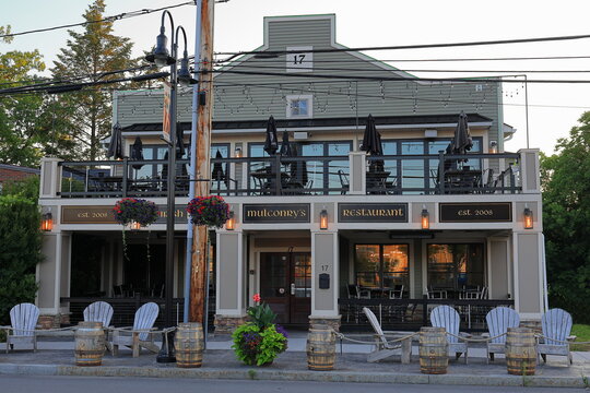 Fairport, NY, USA - July 2nd 2025 - Mulconry's Irish Pub in the Village of Fairport, reflecting the sun's red and orange rays in the morning light.
