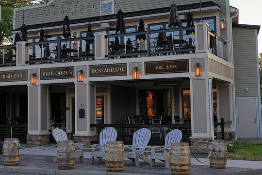 Fairport, NY, USA - July 2nd 2025 - Mulconry's Irish Pub in the Village of Fairport, reflecting the sun's red and orange rays in the morning light.