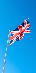 Obraz premium Union Jack flag waving majestically against a clear blue sky, emblem, symbol