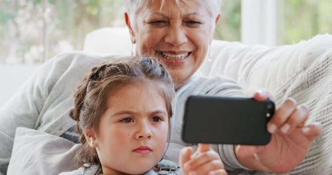 Grandmother, girl and relax in house with phone, online game and bonding together on weekend break. Happy, old woman and grandchild play on sofa with tech, scroll and browsing internet for kids app.