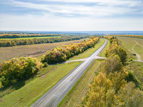 Aerial view of asphalt highway between protective shelterbelts on agricultural lands in autumn Kemerovo region Kuzbass