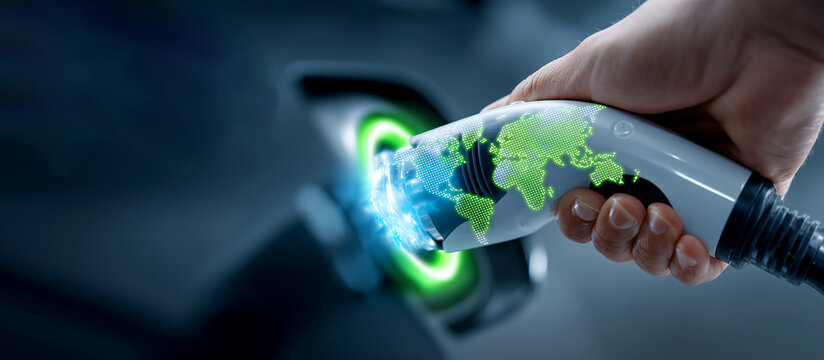 Hand Holding EV Charging Connector with Glowing Green World Map Overlay for Global Sustainable Energy Concept