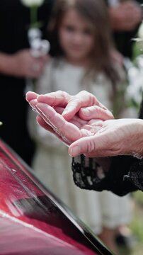 Elderly, hands or widow with ring on coffin for death, grief or condolences at funeral. Senior, partner and finger with jewelry in cemetery for relationship depature, farewell or respect in graveyard