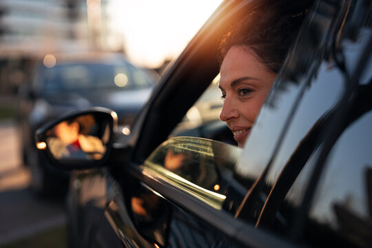 Woman driving car smiling during sunset commute