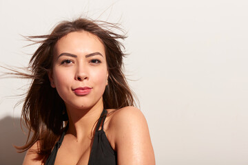 Young white adult woman one person in black bikini portrait with wind blown hair looking at camera indoors studio. Concept of beauty, natural confidence and summer fashion lifestyle