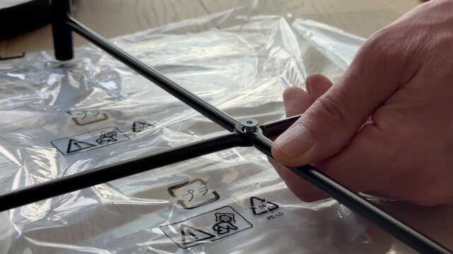 Hands insert bolt into metal frame and tighten using hex key tool. Fingers screw fastener into structure during furniture assembly process. Concept diy, build, home setup..