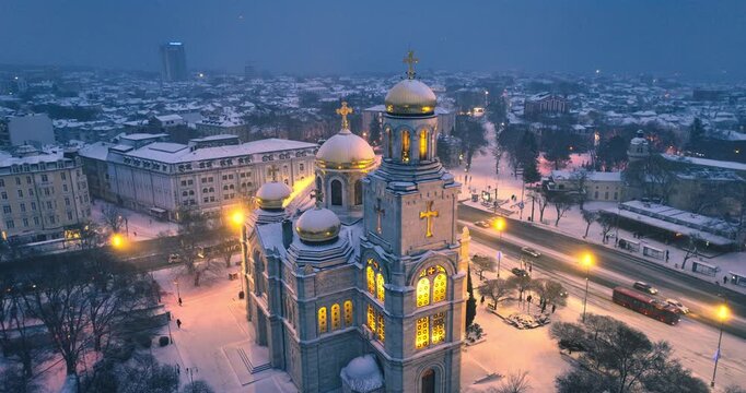 Aerial drone view of city center in Varna, Bulgaria and Illuminated church The Cathedral of the Assumption covered in snow cinematic winter urban landscape video
