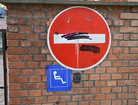 Graffitied No Entry Sign and Disabled Access Symbol on Weathered Brick Wall
