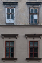 Obraz premium Old Building Facade With Weathered Windows and Rustic Architectural Details in Urban Setting