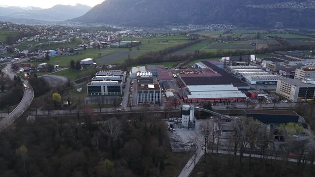 Drone flying laterally over industrial zone with factory buildings and rooftop solar panels. Sustainable energy and modern infrastructure concept.