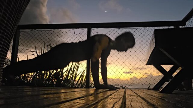 silhueta de homem fazendo exerc&iacute;cios ao nascer do sol 
