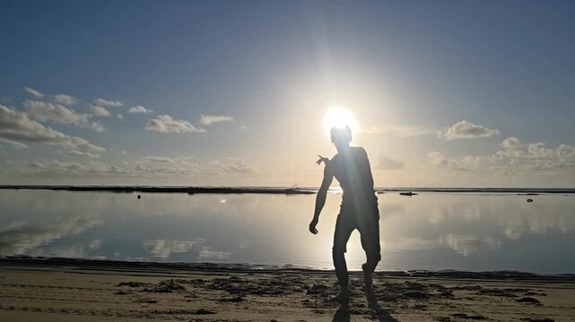 silhueta de homem jogando capoeira na praia 