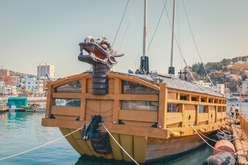 Traditional turtle ship docked at Tongyeong harbor in Namhae South Korea showcasing Korean naval heritage with wooden structure and dragon head. Scenic historic port and tourism landmark view. © humanaut