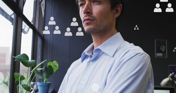 Animation of profile icons floating over thoughtful man looking out of window at office