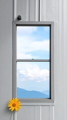 Fototapeta premium Window view of blue sky and mountain range with yellow flower in foreground creating a peaceful optimistic mood for travel and reflection