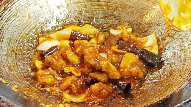 Cooking Thai stir-fried chicken with cashew nuts (Gai Pad Med Mamuang) in a hot metal wok.