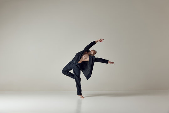 Dancer balancing on one leg with extended arms in clean studio space. Concept of stability, body control, contemporary dance practice and artistic expression in minimal environment