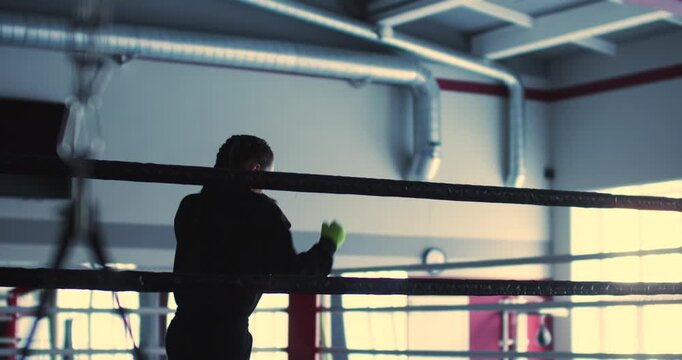 In the boxing gym, a teenage female athlete executes shadow fighting with speed and accuracy, committed to elevating her boxing performance. Slow motion 4k footage.