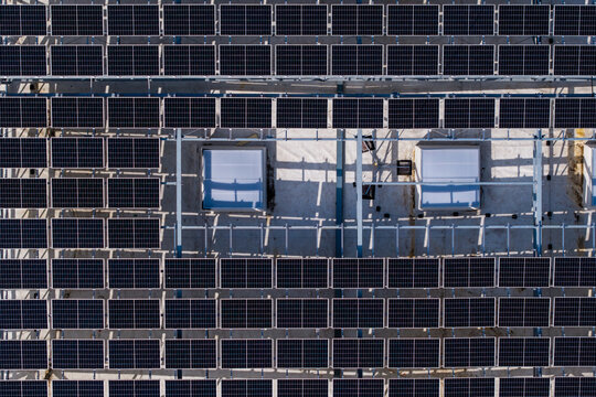 Aerial view of solar panels in a grid-like pattern, creating a stark contrast of light and shadow, Warsaw, Masovian Voivodeship, Poland.