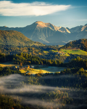 View of golden light kissing the rolling hills and majestic Triglav mountains, with soft mist weaving through the valleys in Spodnja Lu&Aring;&iexcl;a, Selca, Skofja Loka, Slovenia.