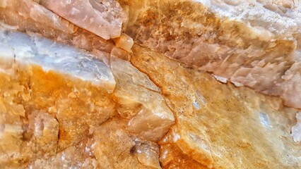 Obraz premium Close-up abstract texture of wet raw stalactite cave rock formations with orange and white colors