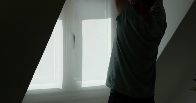 Seeking Solitude in Silhouette: A solitary figure, cloaked in shadow, reaches towards the bright light streaming through a window, inviting introspection and contemplation.