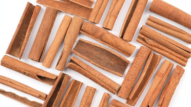 Macro rotating cinnamon sticks isolated on white background. Clean organic spice texture for baking, culinary and traditional medicine projects.