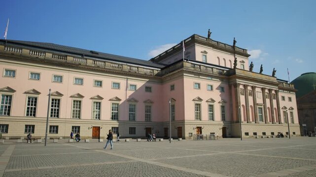 BERLIN, GERMANY - MARCH 23 2026: Panning shot of the historic Staatsoper Unter den Linden (Berlin State Opera) featuring its neoclassical facade and the St. Hedwigs Cathedral in the background