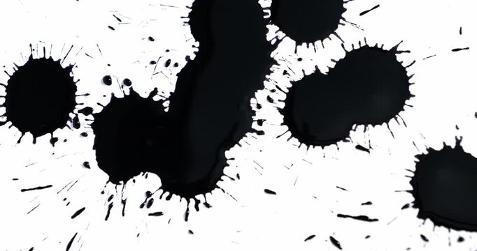 Black spots on a white background. Ink spills onto white paper. Black drops and white surface.