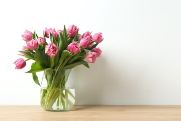 Fototapeta premium Beautiful pink tulips in a vase on wooden table. Mother's Day concept