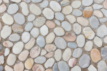Smooth pebble mosaic floor made of rounded river stones set into grout, offering a natural textured surface ideal for walkways, patios, garden paths and decorative architectural finishes © evannovostro