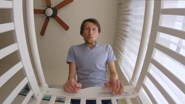 Funny inexperienced father reacts with disgust after noticing his baby soiled the diaper and awkwardly begins changing it. Shot from baby's point of view. Slowmotion video.