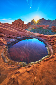 Redstone Dune Sunrise Sunburst Over Desert Tinaja Rock Basin and Water Reflection