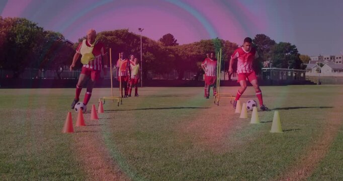 Two players starting dribbling drill through cones and poles on grassy pitch for soccer training