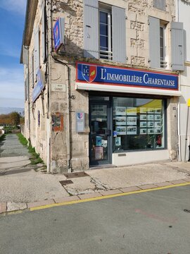 Saujon, France - November 10, 2025: L'Immobiliere Charentaise real estate agency storefront with stone facade and large windows showcasing property listings in a charming French village