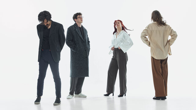 Group of young people posing in different directions in clean studio space. Concept of individuality, social dynamics, fashion styling, and modern lifestyle branding