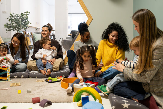 Diverse parents and children are engaging in activities and playing with toys on the floor