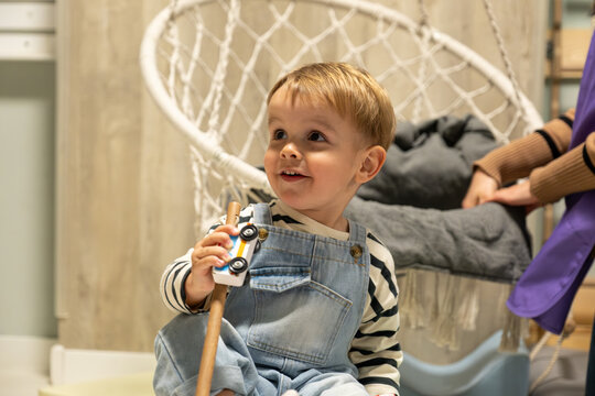 Happy toddler smiling and playing with a wooden car indoors