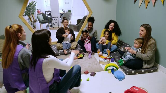 Mothers and their children enjoying music and games during a kindergarten group activity with teachers