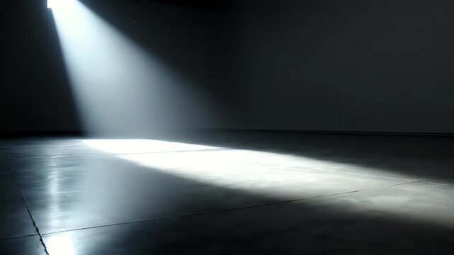 Bright sunlight illuminates cold concrete floor in empty dark room through small window creating stage style view with strong shadows and mysterious mood inside silent abandoned stone building