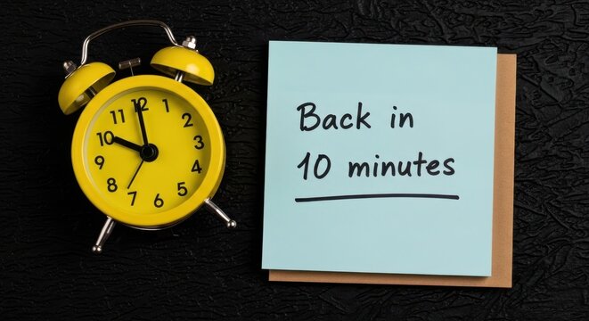 Yellow vintage alarm clock with back in 10 minutes note, blue sticky note on black background, time management and break concept