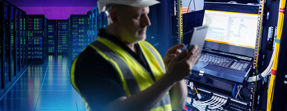 IT infrastructure maintenance, technician checks server rack and monitors network data on mobile device. Data center equipment diagnostics and system administration work.