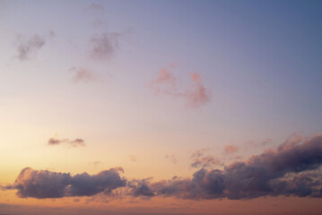 Fototapeta premium A background image of an orange-blue sky with dark clouds at sunset on a winter evening. Beautiful gentle sunset.