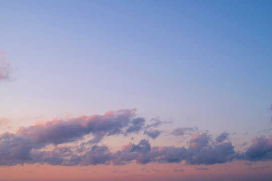 A background image of an orange-blue sky with dark clouds at sunset on a winter evening. Beautiful gentle sunset.