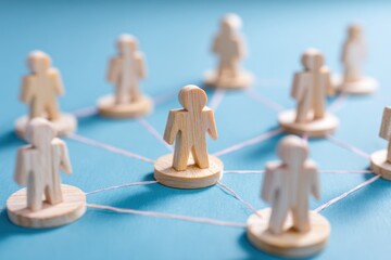 Obraz premium Networked Relationships: Wooden figurines connected by lines, representing interconnectedness and communication in a blue setting.