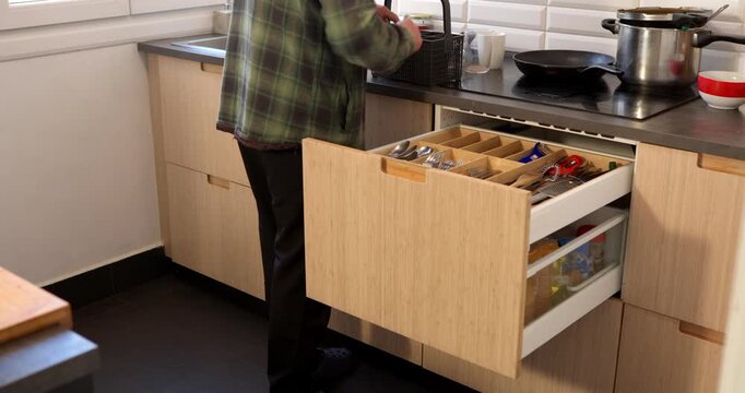 Culinary Workspace: A person reaches into the drawer in the home kitchen, the epitome of functionality and design.