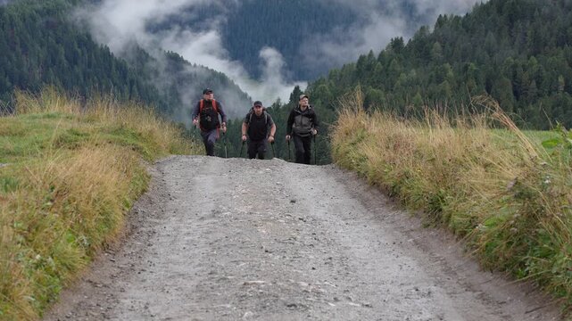 Three tourists on a hike in the Geisler National Park. Italy. Dolomites.