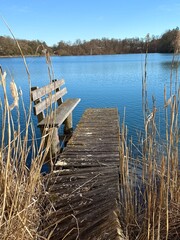 Fototapeta premium small bench on the wooden pier over the blue lake