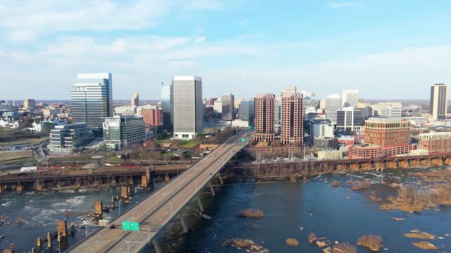 Richmond, Virginia skyline featuring the Manchester Bridge crossing the James River rapids into the downtown financial district. 4k aerial cinematic video.